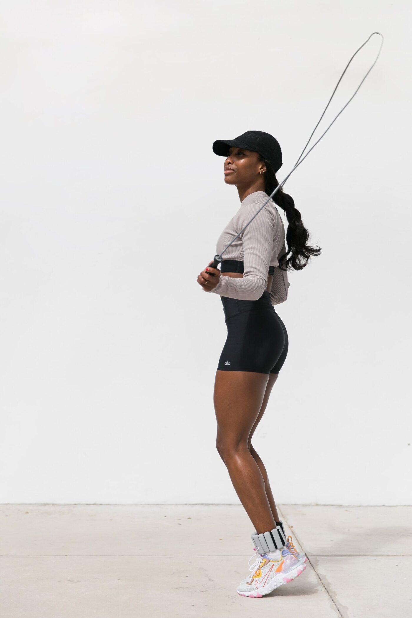 Francia Cooper jumping rope in a black cap, long-sleeve top and shorts