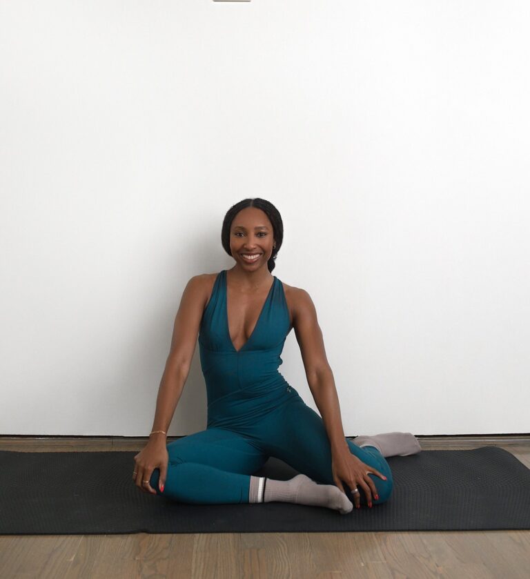Francia Cooper sitting cross-legged on a mat
